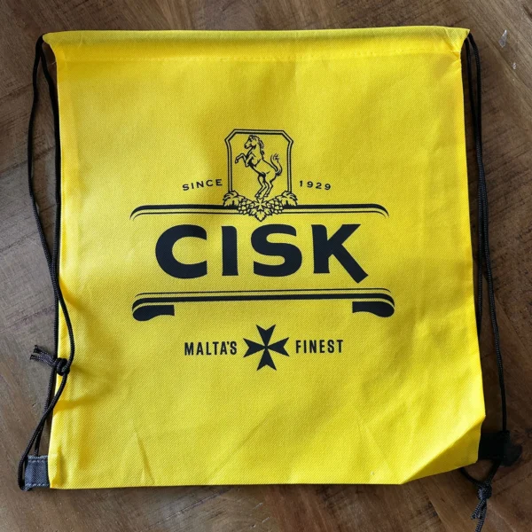 Gelber Cisk Turnbeutel mit schwarzem Cisk-Logo und Malteserkreuz
