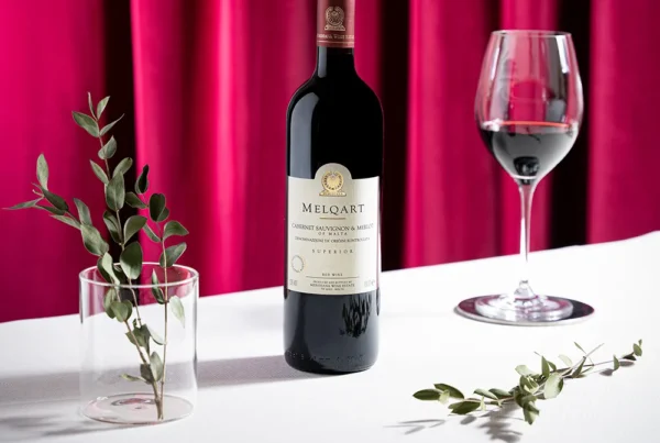 Flasche Melqart Cabernet Sauvignon & Merlot neben gefülltem Rotweinglas