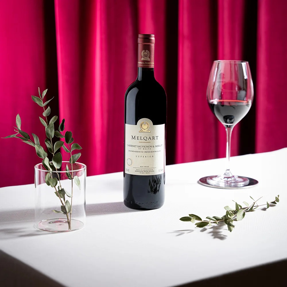 Flasche Melqart Cabernet Sauvignon & Merlot neben gefülltem Rotweinglas