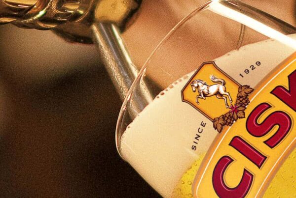 Cisk Lager wird aus der Flasche in ein Glas mit Cisk-Logo eingeschenkt